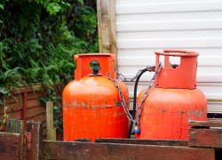 Gas canisters for a caravan or motorhome leaning up against a building. Tips and ideas from Webbs for embracing off-season weather in your motorhome, caravan or camping travels.