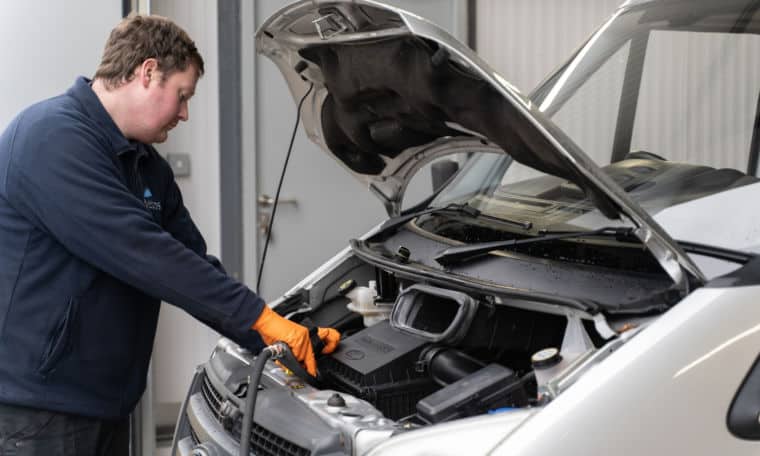 Service team testing an engine battery on a motorhome.