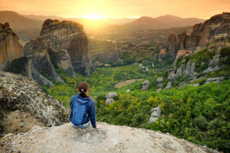 Camper sat on a cliff looking across at sunset. 5 Reasons Why Camping Is Good For You by Webbs.