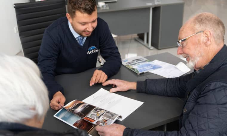 Webbs Sales staff and customer looking through a caravan brochure.