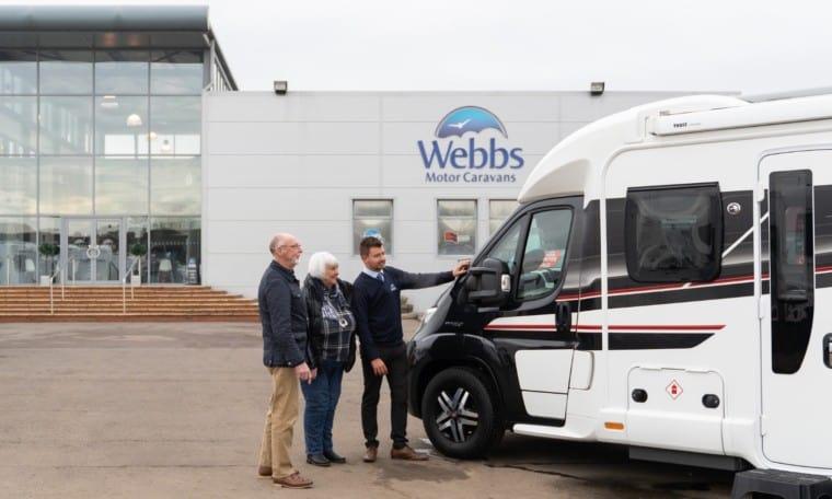 Sales staff and customers in the Webbs Motor Caravans' forecourt viewing a pre-owned motorhome.