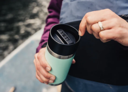 A person holding a YETI tumblr in wet weather, from Webbs Outdoors. Tips and ideas from Webbs for embracing off-season weather in your motorhome, caravan or camping travels.