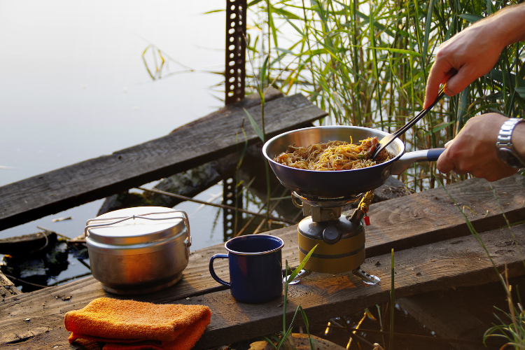 A person cooking a meal on some camping cooking equipment