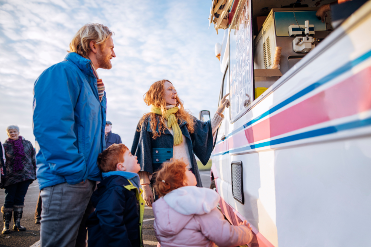 A family at a food truck at an event. Family Friendly Motorhome and Caravan Holiday Ideas by Webbs.