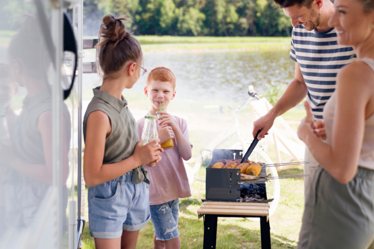 A family cooking food by their vehicle. Why a Touring Holiday is a Great Value for Money Option in 2023 by Webbs.