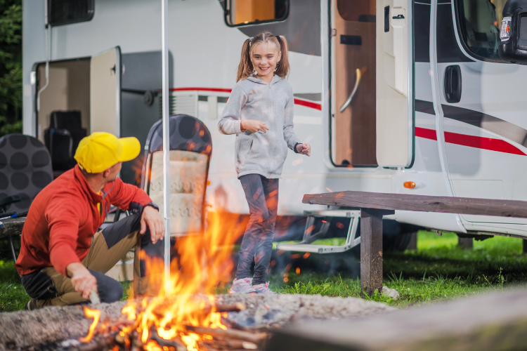 A family by their motorhome and campfire exploring their local area. Why a Touring Holiday is a Great Value for Money Option in 2023 by Webbs.
