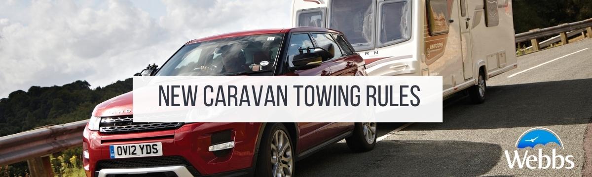 An approaching car towing a caravan on a road beside a view. New Caravan Towing Rules by Webbs.