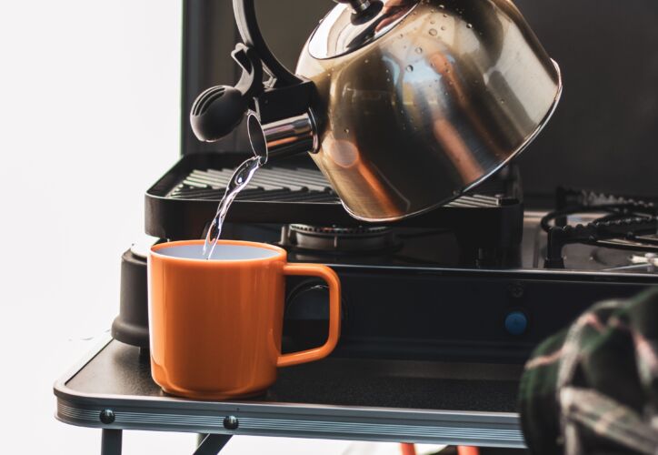 Kettle pouring hot water into a mug. Discover caravan accessories for sale at Webbs.