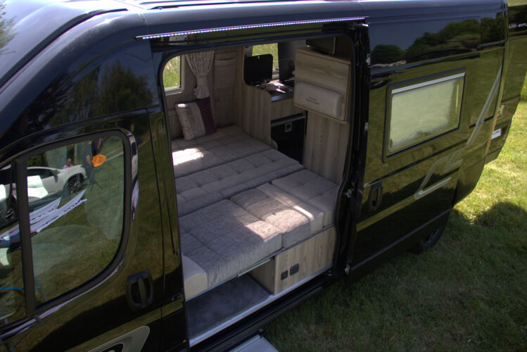 Outside view showing the interior of an Auto-Explore van conversion, displaying the layout of the bed.