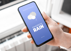 A phone showing a rainy weather forecast. Tips and ideas from Webbs for embracing off-season weather in your motorhome, caravan or camping travels.