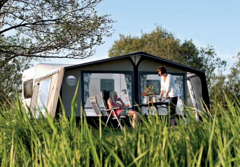 A motorhome awning in a grassy field.