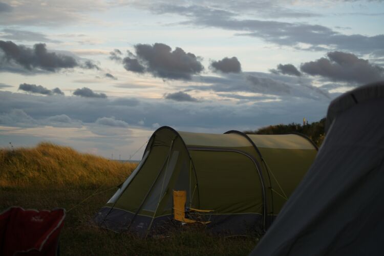 Two tents set up outside in a field with grey clouds above. How To Plan Your Perfect Motorhome Getaway by Webbs.