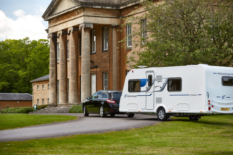 A Pegasus caravan being towed by a grand building. Top 5 tips for new caravan owners blog by Webbs.