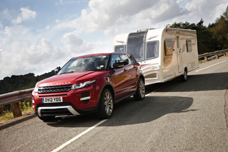 A car towing a Bailey caravan on a road. Bailey of Bristol Brand Showcase by Webbs.